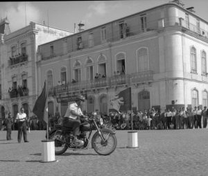 Fotografia da autoria de Américo Ribeiro, com o código de referência PT/AFAMR/FAR/NTR/04301, do Arquivo Municipal de Setúbal, que ilustra uma das inúmeras atividades realizadas pela FNAT, mostrando-se aqui uma gincana de motas realizada na Avenida Luísa Todi, no verão de 1956.